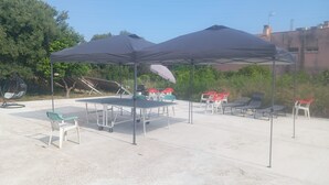 An outdoor seating area with tables and chairs, shaded by large umbrellas.