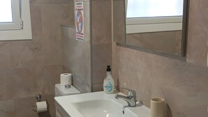 A bathroom with a white sink, a toilet, a bathtub, and a mirror.