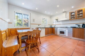 A kitchen with white cabinets, a wooden dining table, and a window.