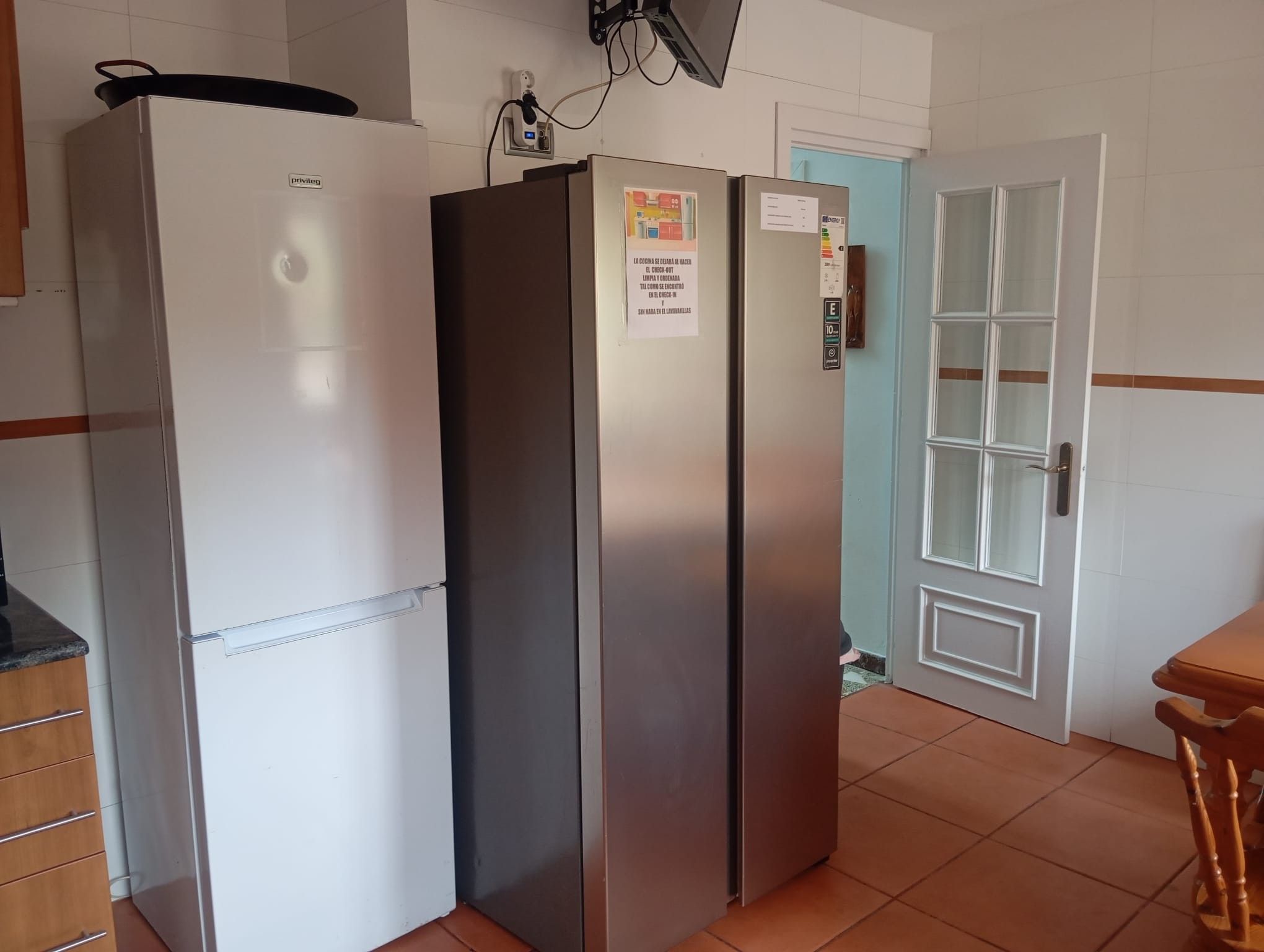 Una cocina con un refrigerador blanco, un refrigerador de acero inoxidable y un armario de madera.