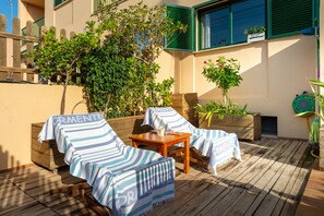 A sunlit outdoor seating area with striped covers, wooden furniture, and potted plants. - Apartment 'Es Pujols' with Private Terrace, Wi-Fi and Air Conditioning (Es Pujols)