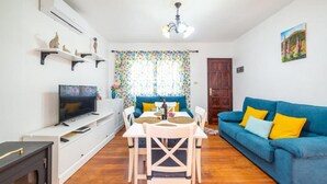 Un salon avec un téléviseur, un canapé et une table à manger.