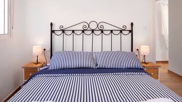 A neatly made bed with striped bedding, two bedside tables with lamps, and a simple headboard.
