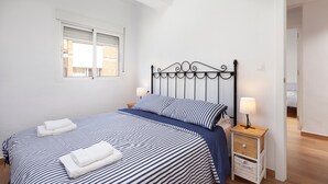 Una camera da letto con un letto, due comodini, una finestra e una porta che dà su un'altra stanza.