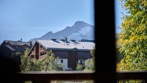 Un edificio in legno tradizionale con tetto spiovente, circondato dal verde e con montagne sullo sfondo.