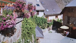 Un borgo montano con edifici in pietra, una recinzione in legno e un balcone fiorito.
