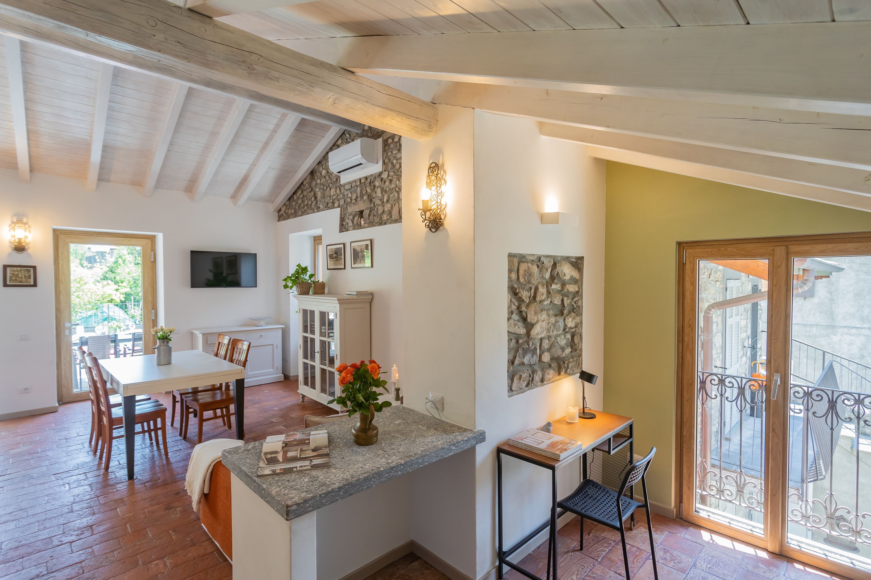 Een ruime keuken met een eethoek, een accentmuur van steen en een balkon met een sierhekwerk.