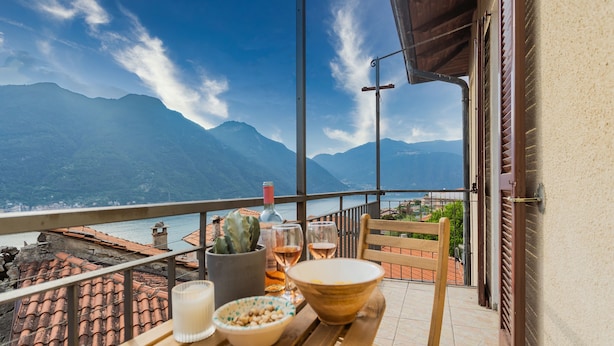Varanda com mesa posta para dois, com vista para uma paisagem montanhosa.
