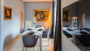Uma sala de jantar com uma mesa posta para quatro pessoas, um espelho grande e obras de arte nas paredes.