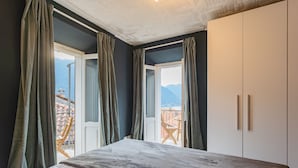 Quarto com cama, janela e vista para montanhas.