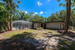 A single-story house with a covered outdoor area, a swimming pool, and a well-maintained lawn.