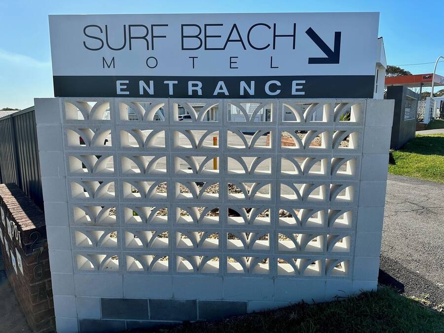 A sign for Surf Beach Motel with an entrance gate.