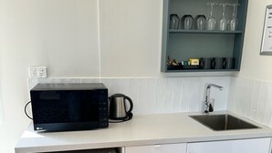 Una cocina compacta equipada con microondas, cafetera, lavaplatos y un refrigerador pequeño.