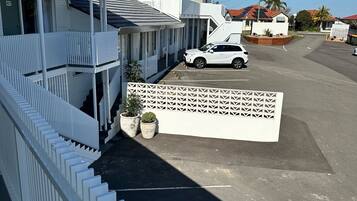 A residential area with a white house, a white car parked in front, and a white fence.