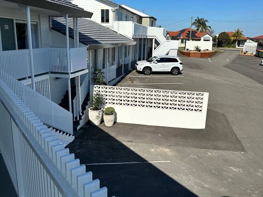 A residential area with a white house, a white car parked in front, and a white fence.