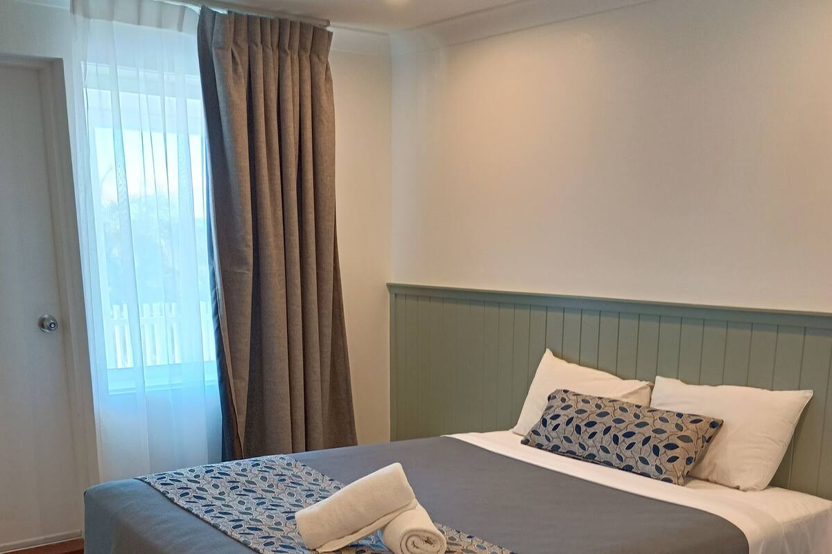 Ett hotellrum med en säng, gardiner och ett fönster.