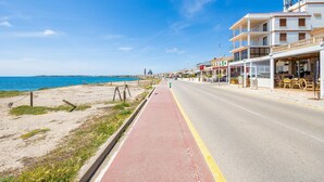 A coastal road with a red bike lane, beachfront properties, and a clear blue sky. - Apartment 'Brisas Vista Mar' with Sea View, Wi-Fi and Air Conditioning (Sa Ràpita)