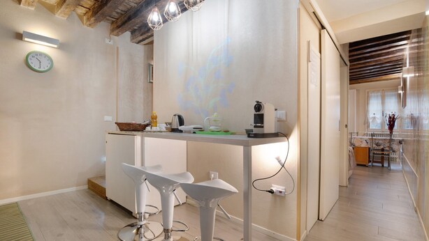 A modern kitchen with a central island, bar stools, a clock, and a projection on the wall. - Vacation Home "Ca' Lirica" with Wi-Fi & A/C (Venezia)