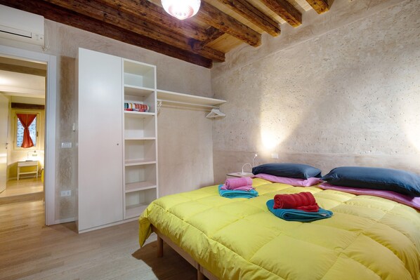 Une chambre à coucher comprenant un lit, une armoire, une table de chevet et une fenêtre avec des rideaux.