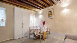 A dining area with a table set for four, a white wardrobe, and a painting on the wall. - Vacation Home "Ca' Lirica" with Wi-Fi & A/C (Venezia)