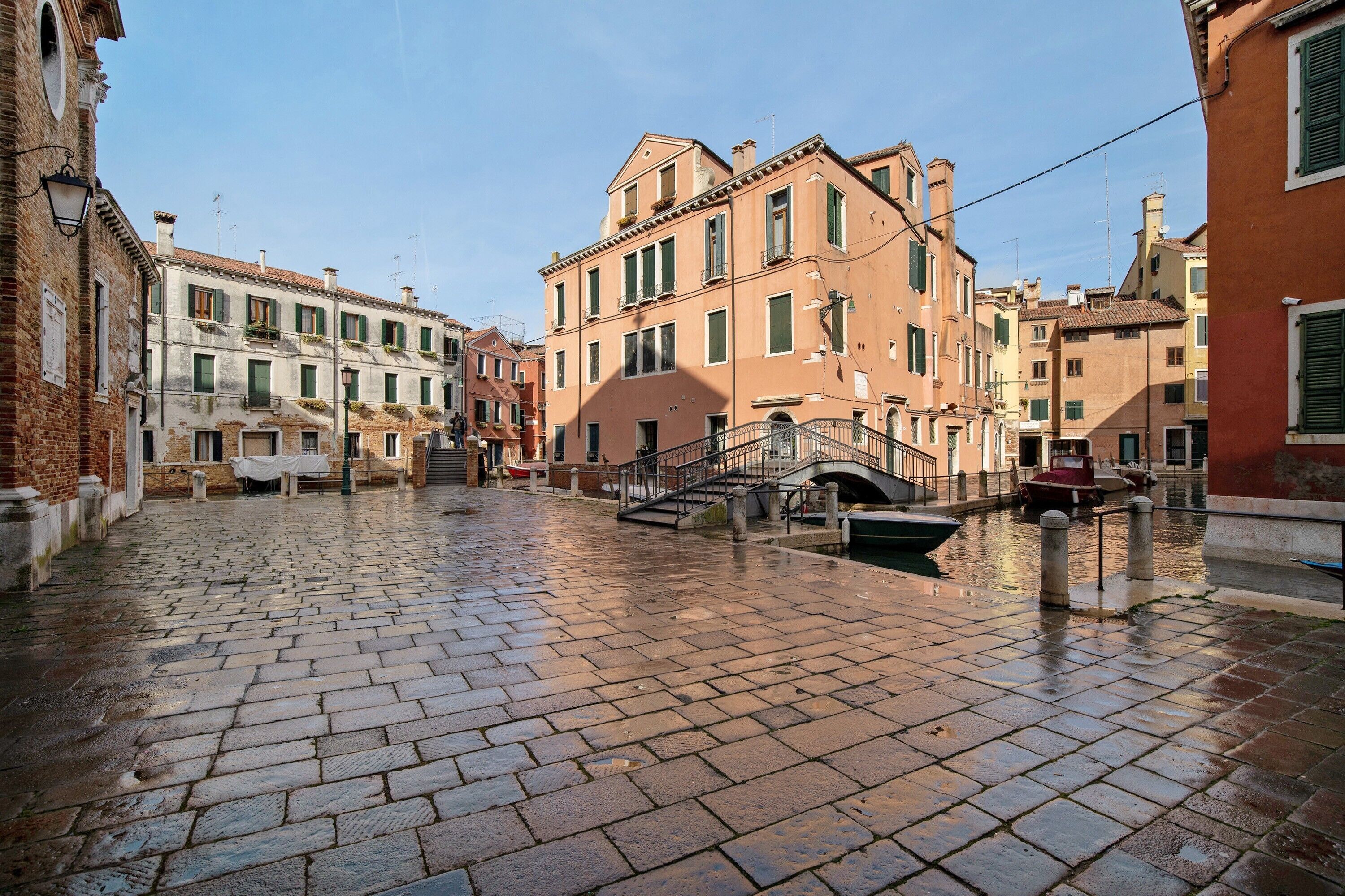 A historic street with cobblestone pavement, traditional buildings, and a small bridge.