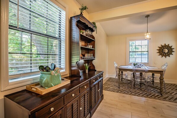 A kitchen with a wooden cabinet, a dining table with chairs, and a window with blinds.