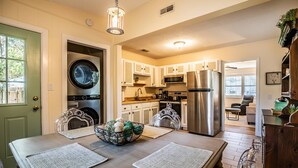 Una cucina moderna con elettrodomestici in acciaio inossidabile, una zona pranzo con tavolo e sedie, e vista sul soggiorno.