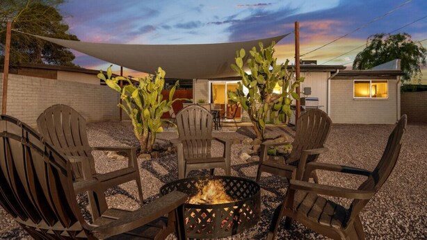 An outdoor patio with a fire pit, wooden chairs, and a table. - Central / Remodeled / Fenced / Clean / 3 BR 2 BA (Tucson)