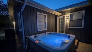 A hot tub on a wooden deck with a house in the background. - Four bedroom with hot tub and views! (Kerrville)
