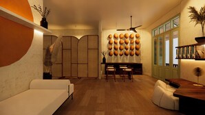 A modern living room with a sofa, a dining table with chairs, a ceiling fan, and a wall decorated with coconuts.