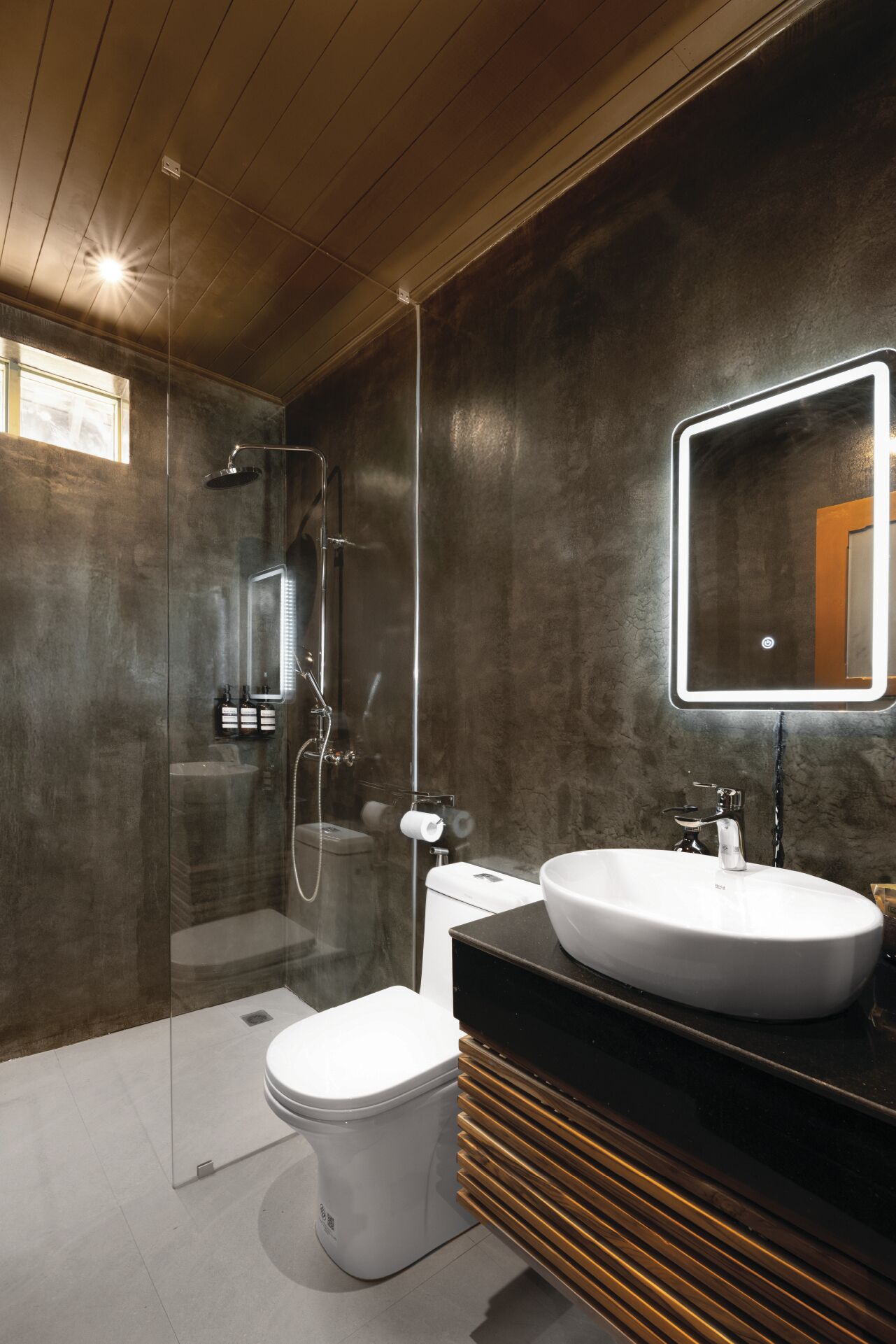 Un baño moderno con ducha acristalada, inodoro blanco y tocador con un espejo grande.
