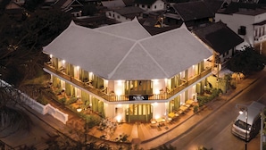 A two-story building with a white tiled roof and a sign reading "NAVA LEIANG PRABANG".