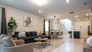 Een moderne woonkamer met een bank, salontafel en een eethoek.