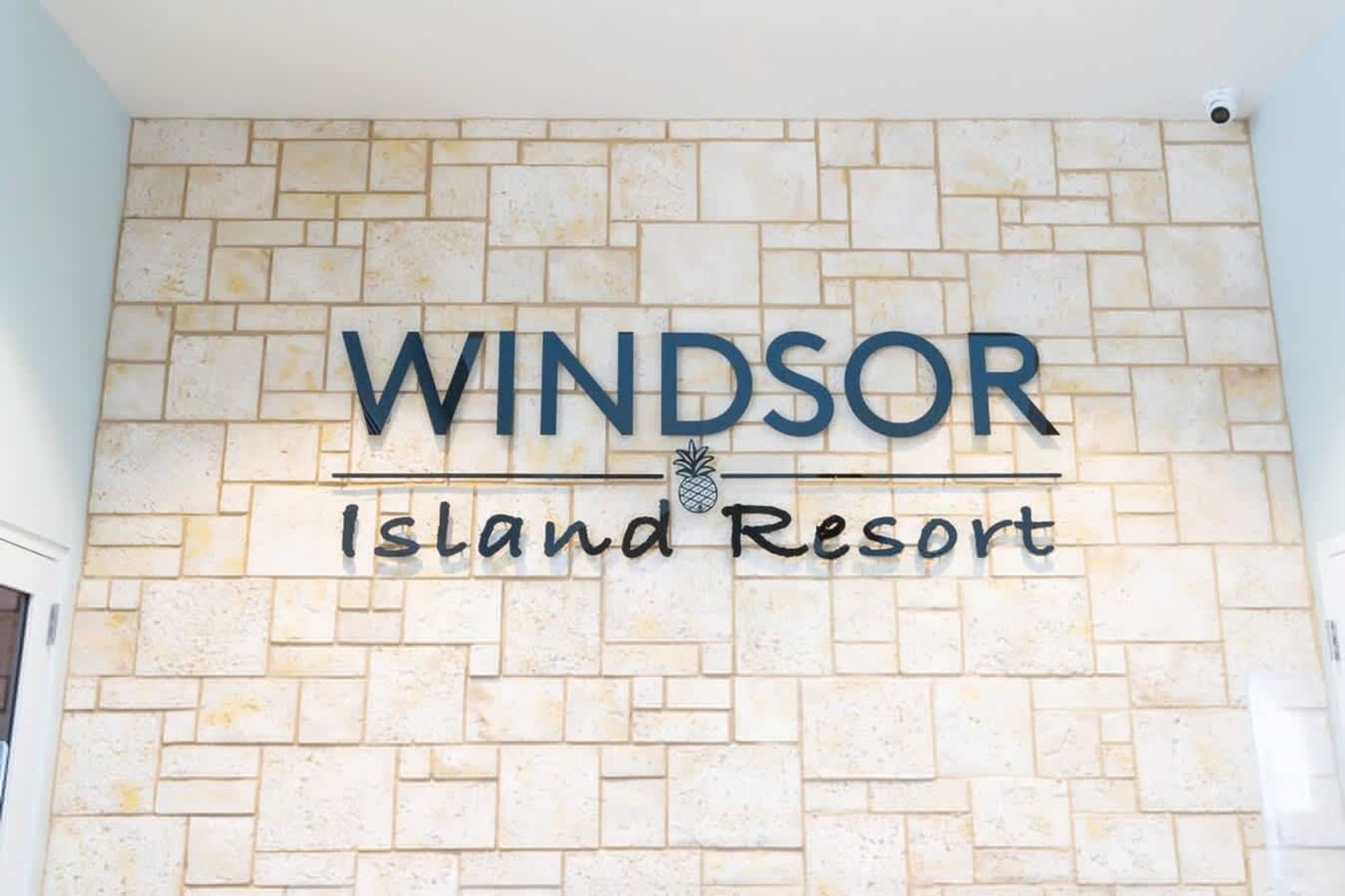 A sign with 'WINDSOR Island Resort' on a brick wall.