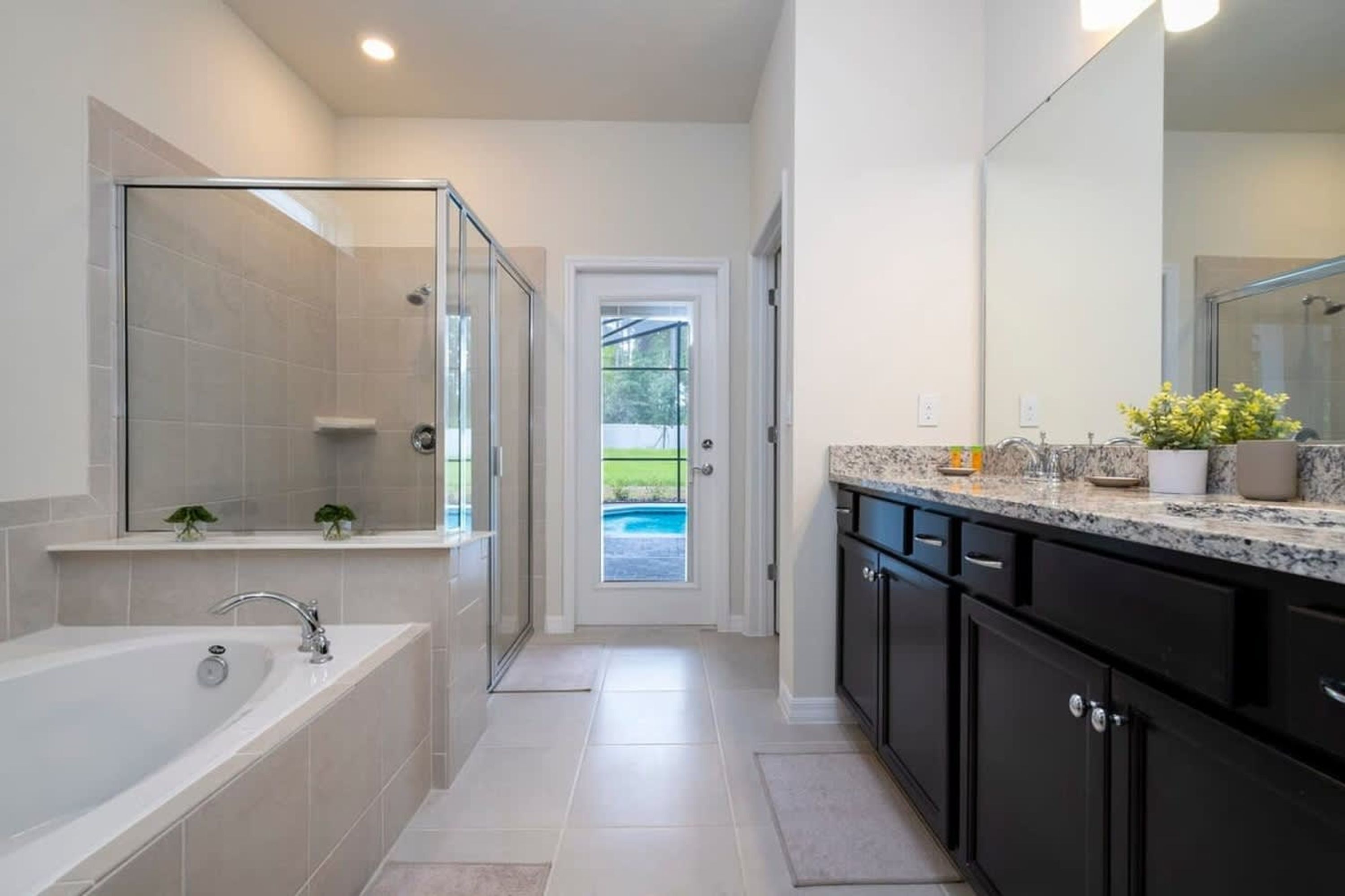A modern bathroom with a glass-enclosed shower, a bathtub, and a vanity with a large mirror.