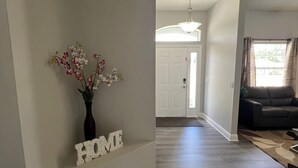 A spacious living area with a dark wood floor, a sofa, and a vase with flowers on a wall. - Modern and spacious getaway with a pool and grill (Cocoa)