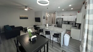 A modern kitchen with a central island, white cabinets, and stainless steel appliances. - Modern and spacious getaway with a pool and grill (Cocoa)