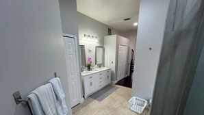 A modern bathroom with a double sink vanity, a large mirror, and a towel rack. - Modern and spacious getaway with a pool and grill (Cocoa)