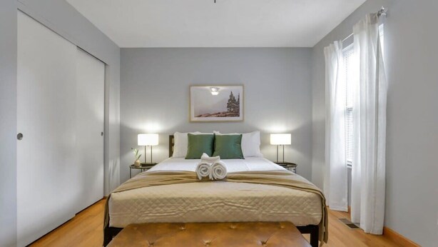 Une chambre d’hôtel avec un lit, des lampes de chevet, un tableau au mur et une fenêtre avec des rideaux.
