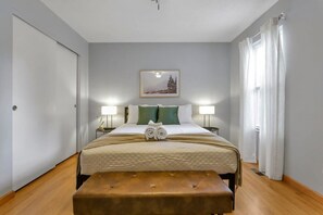 A hotel room with a bed, bedside lamps, a picture on the wall, and a window with curtains.