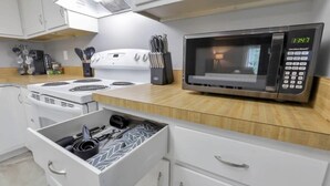 Une cuisine moderne équipée d’un four à micro-ondes, d’une cuisinière et d’un tiroir contenant des ustensiles de cuisine.