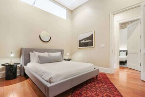 Relax in this serene bedroom with a large bed, round mirror, and framed artwork.