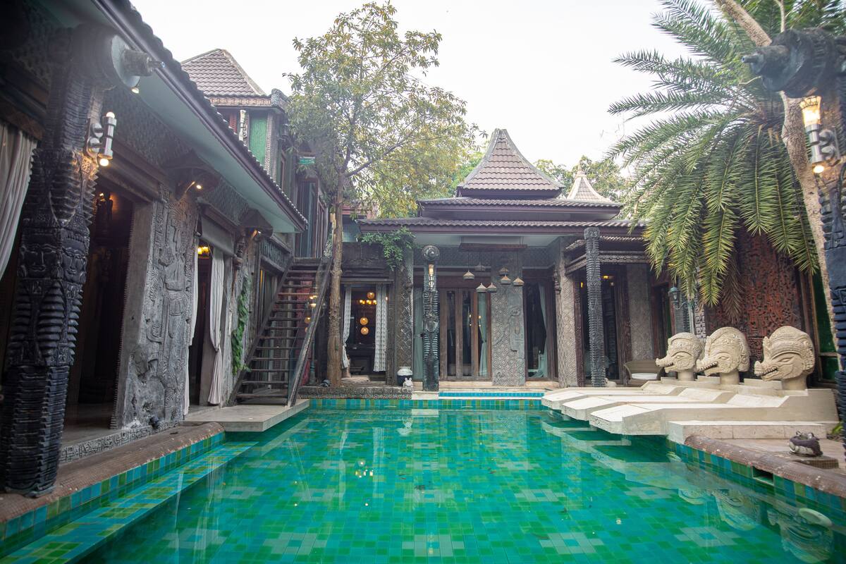 Un bâtiment traditionnel doté d’une piscine, de sculptures en pierre et d’un toit recouvert de tuiles.
