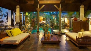 Eine geräumige Lobby mit Pool, Holzmöbeln und tropischer Bepflanzung.
