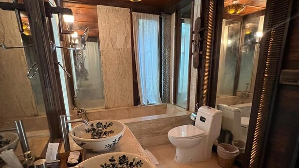 Een badkamer met twee grote, versierde wastafels, een toilet en een douche.