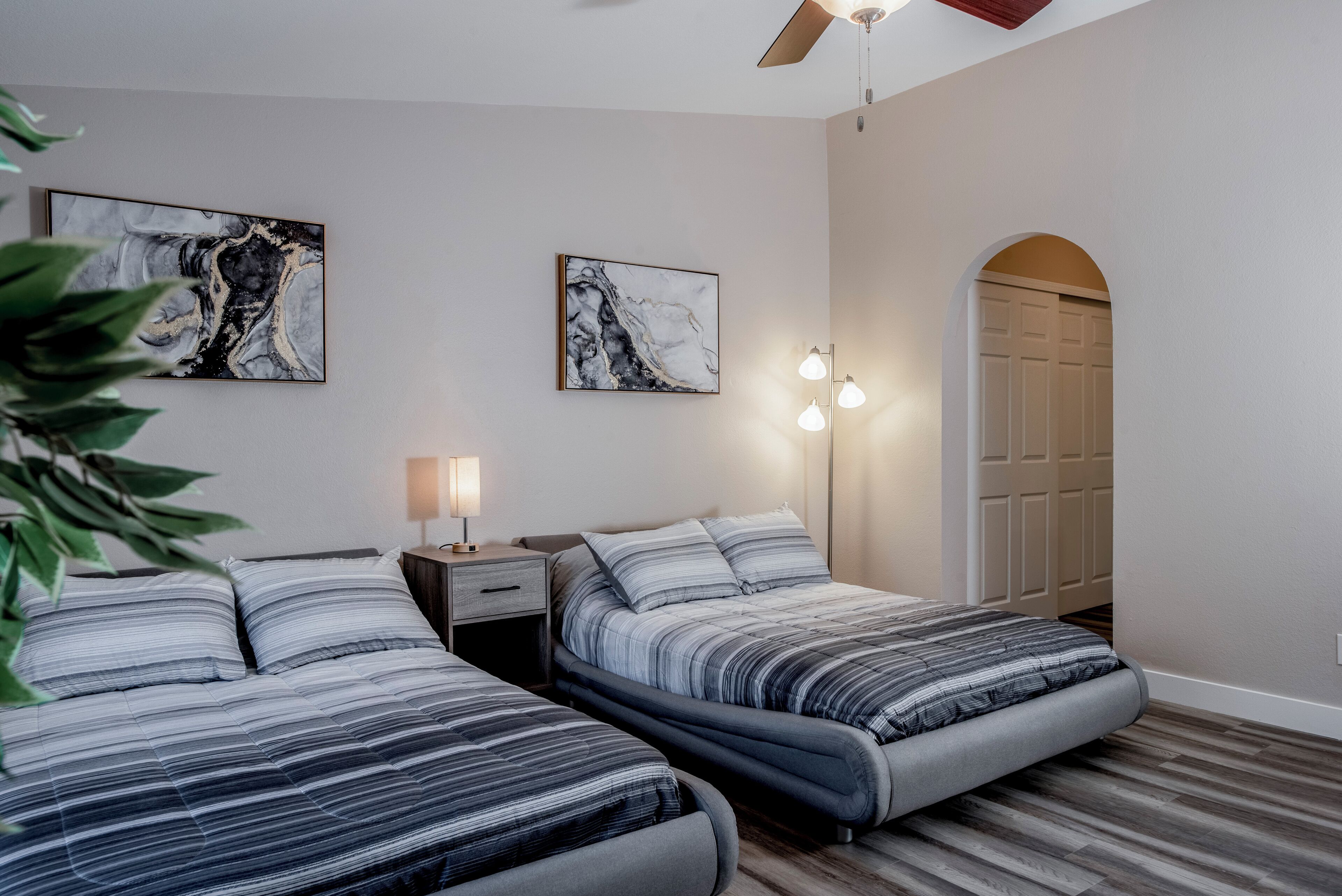 Een slaapkamer met twee bedden, een nachtkastje, een lamp en twee wandlampen.