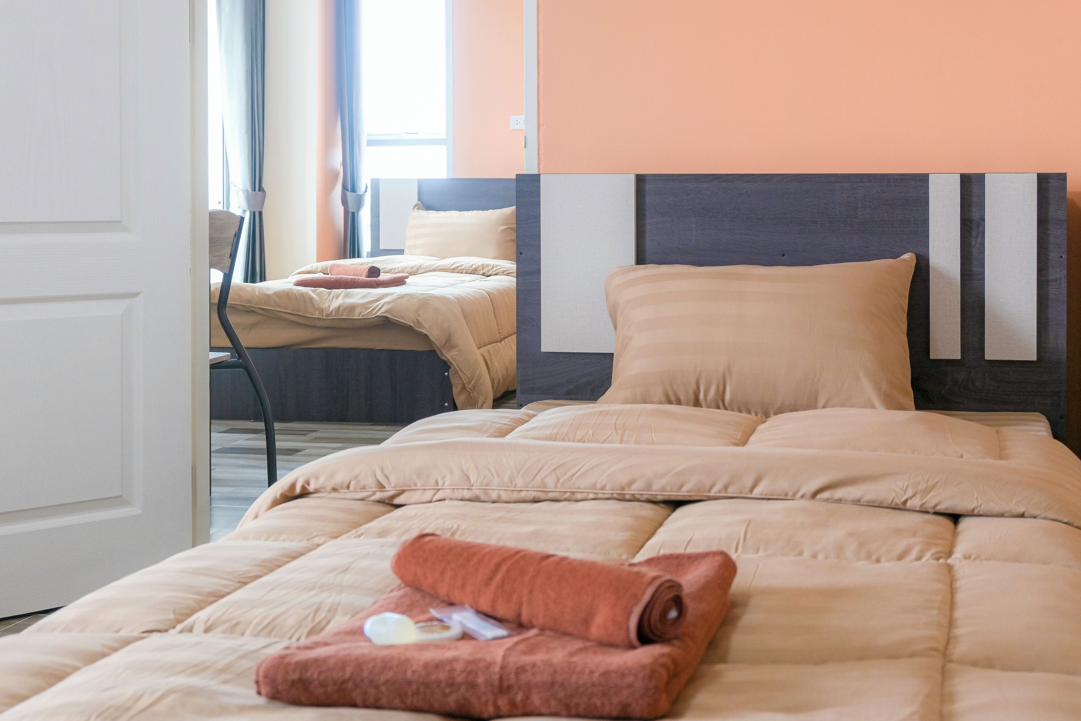 A hotel room with a large bed, a smaller bed, and a chair.