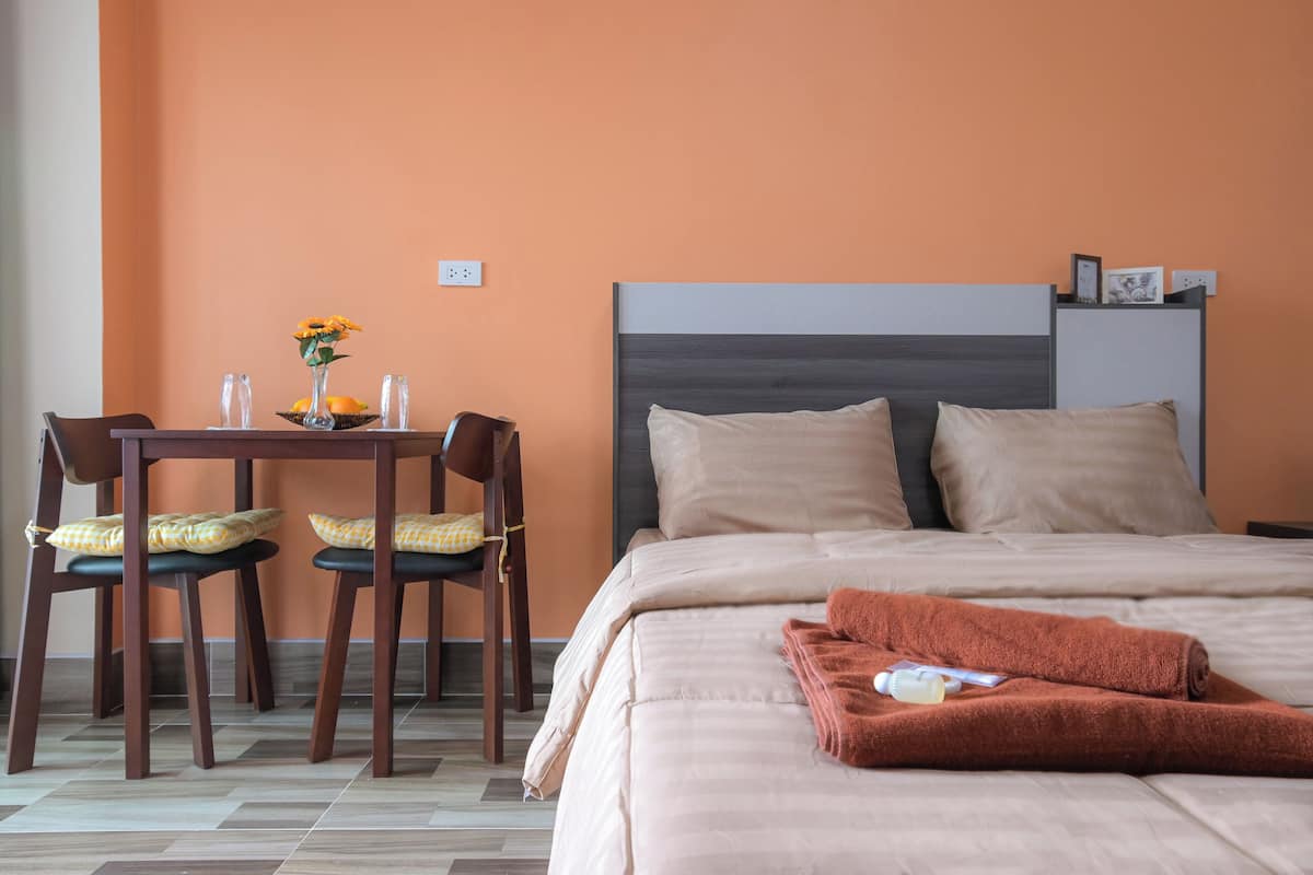 A hotel room with a bed, a table with chairs, and a vase with flowers.