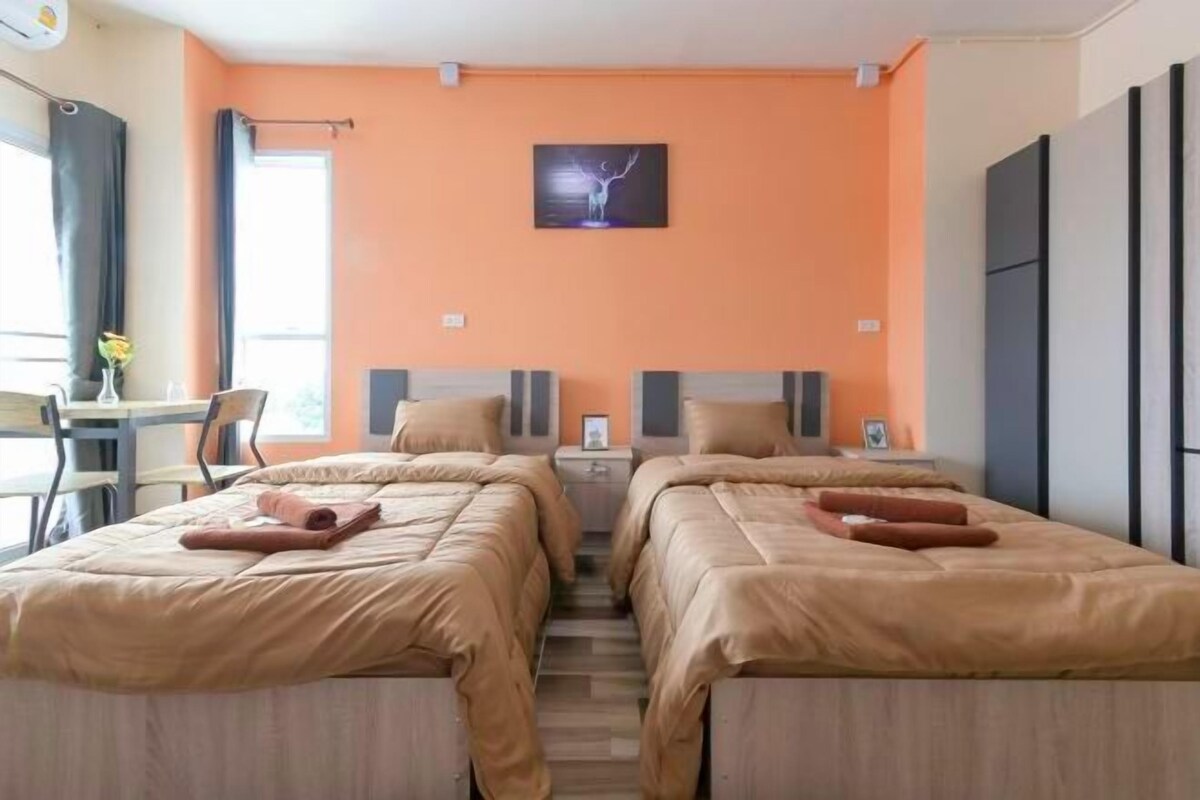 A hotel room with two beds, a desk, and a chair.