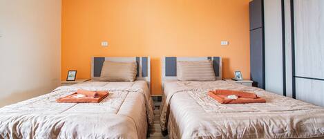 A hotel room with two beds, each with a neatly folded towel and a pillow.